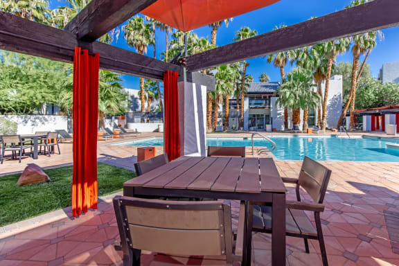 a patio with a table and chairs next to a pool at Evoq Apartment Homes, Las Vegas, 89169