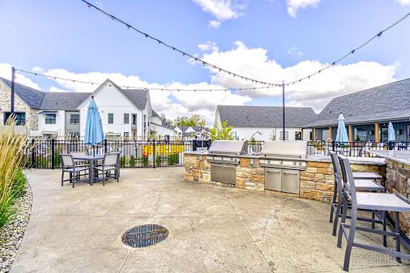 A patio with a table and chairs and a grill. at The BLVD at Wilson Crossings, Wyoming, MI