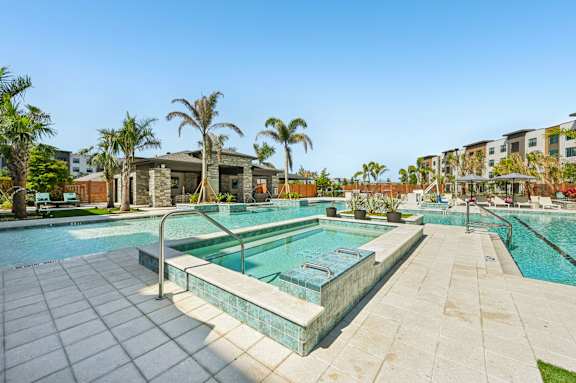 A swimming pool surrounded by palm trees and a building in the background at The Concord Luxury Apartments, Florida, 34240
