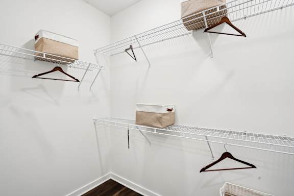 A white closet with three hangers and two boxes on top.