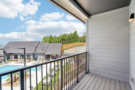 A balcony overlooks a pool and a house.