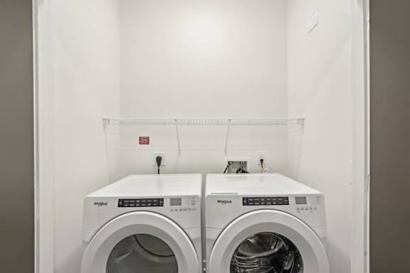 Two white washing machines in a laundry room.