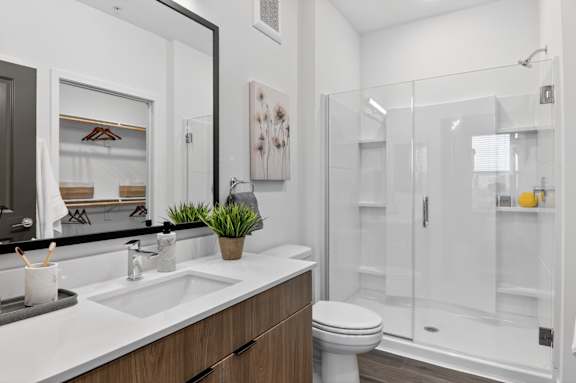 A white toilet sits in a modern bathroom with a large mirror and a walk-in shower.at The Logan Luxury Apartments, Idaho, 83651