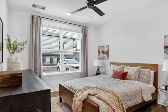 A bedroom with a bed, nightstand, and a plant.at The Logan Luxury Apartments, Idaho, 83651