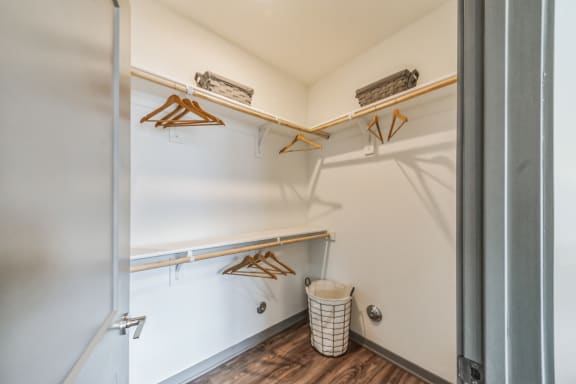 a walk in closet with shelves and a trash can in a room with a door at The BLVD at Wilson Crossings, Wyoming Michigan
