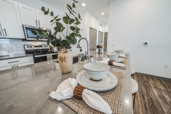 an open kitchen and dining area with white cabinets and stainless steel counter tops at The BLVD at Wilson Crossings, Wyoming, MI