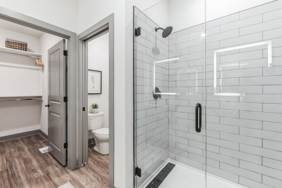 a white bathroom with a shower and a toilet at Meridian at CityPlace, Woodbury, 55125