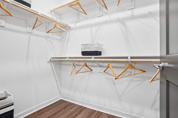 A white wall with a shelf and hangers on it.