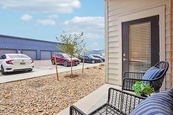 A small tree is planted in a gravel area between two houses.