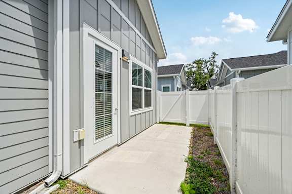 A grey house with a white fence and a white door.