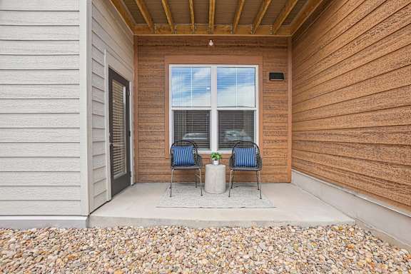 A wooden house with a patio and two chairs.