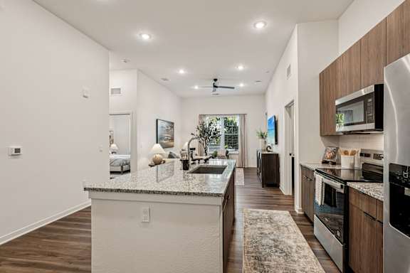 A modern kitchen with a marble countertop and stainless steel appliances at The Stadler Luxury Apartments, Florida