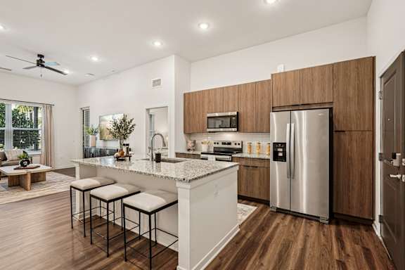 A modern kitchen with a white island and stainless steel appliances at The Stadler Luxury Apartments, Florida 34210