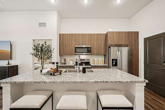A modern kitchen with a granite countertop and stainless steel appliances at The Stadler Luxury Apartments, Bradenton
