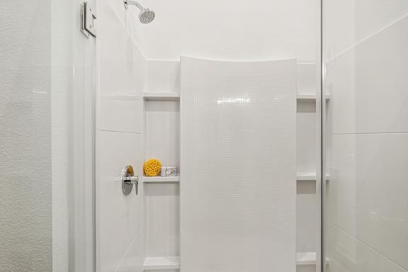 A white bathroom with a shower head and a towel rack at The Stadler Luxury Apartments, Bradenton, Florida