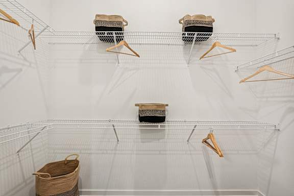 A white wire shelving unit with three shelves and four hangers at The Stadler Luxury Apartments, Bradenton, Florida