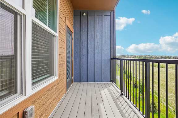 A balcony with a blue door and a wooden floor.