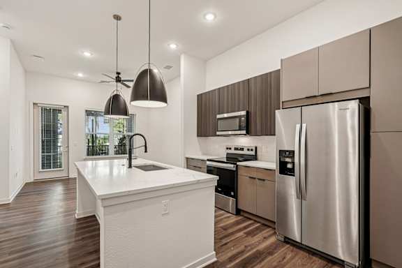 A modern kitchen with a white island and stainless steel appliances at The Stadler Luxury Apartments, Bradenton, Florida