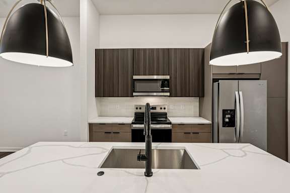 A modern kitchen with a sink and two pendant lights at The Stadler Luxury Apartments, Bradenton, 34210
