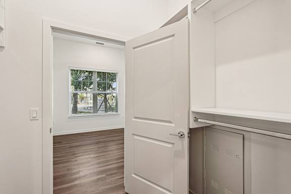 A white door is open to a room with a window at The Stadler Luxury Apartments, Bradenton, FL