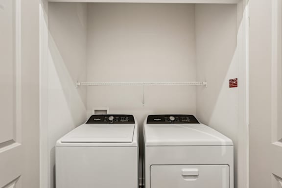 Two white front loading washing machines in a small laundry room at The Stadler Luxury Apartments, Florida