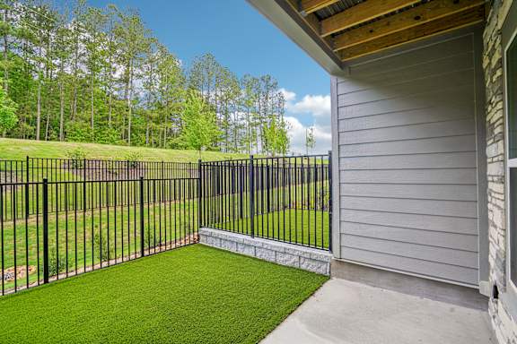 A house has a black fence and a green lawn.