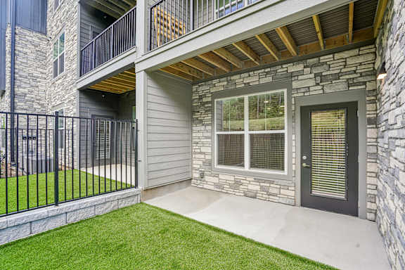 A modern house with a balcony and a stone wall.