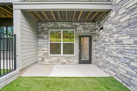 A house with a stone wall and a black gate.