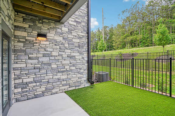A house with a stone wall and a black fence.