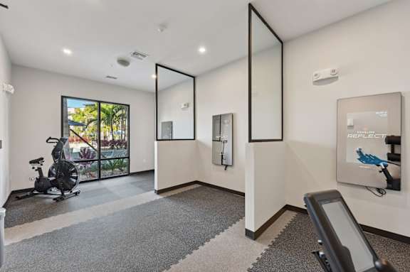 A room with a treadmill and a mirror on the wall. at The Concord Luxury Apartments, Florida, 34240