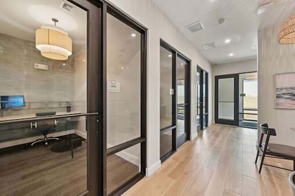A modern office space with glass walls and wooden floors. at The Concord Luxury Apartments, Sarasota