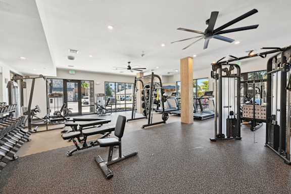A gym with a variety of equipment including treadmills, weights, and a bench press. at The Concord Luxury Apartments, Sarasota