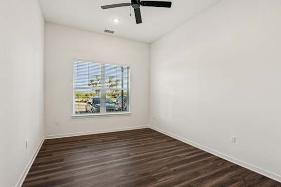 A room with a ceiling fan and a window showing a parking lot outside at The Stadler Luxury Apartments, Florida