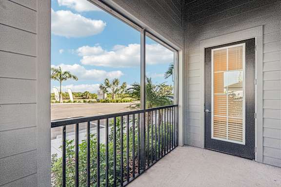 A balcony with a black railing and a view of a street with palm trees at The Stadler Luxury Apartments, Bradenton, FL 34210