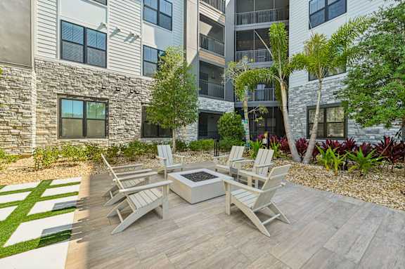 A patio with a table and chairs is surrounded by a garden and a building. at The Concord Luxury Apartments, Florida, 34240