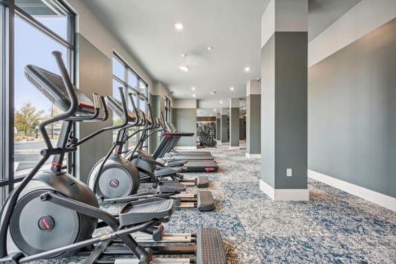 a row of exercise bikes in a fitness room at The Quarry Luxury Apartment Homes, Fort Collins