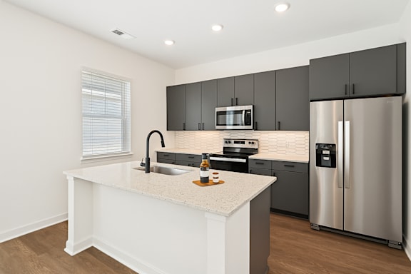 A modern kitchen with a white island and stainless steel appliances.