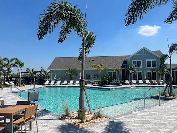A pool area with a palm tree in front of a house. at The Junction at Rockledge Apartments, Rockledge, FL, 32955