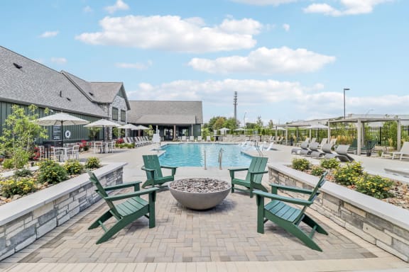 a swimming pool with green chairs and a fire pit at The Depot in The Depot Raymore, MO 64083