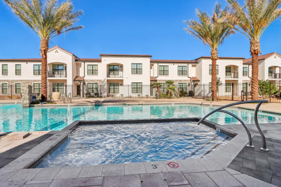 a swimming pool with palm trees and apartments in the background at Stella Luxury Apartment Homes, San Tan Valley, AZ, 85143