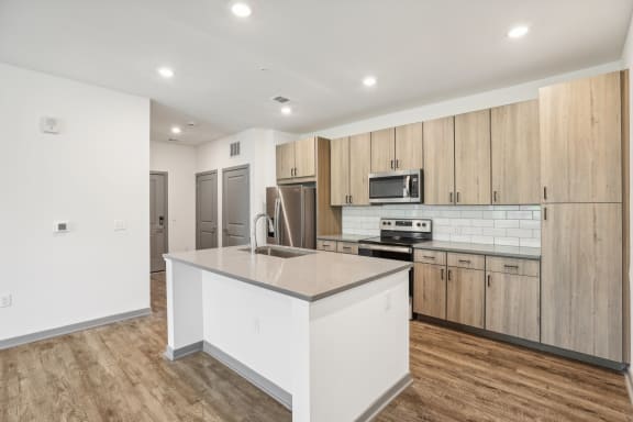 a white kitchen with a large island and wooden floors  at Drift, Daytona Beach, FL, 32117