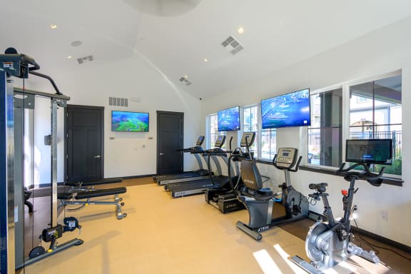a gym with cardio equipment and televisions on the wall   at Oakbrook Townhomes, Franklin, Tennessee