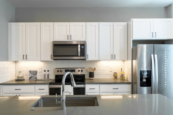 a white kitchen with stainless steel appliances and white cabinets  at Oakbrook Townhomes, Tennessee, 37067
