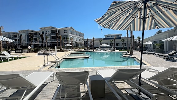 A pool area with sun loungers and a striped umbrella.