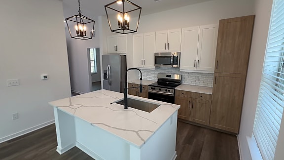 A kitchen with a white island and wooden cabinets.