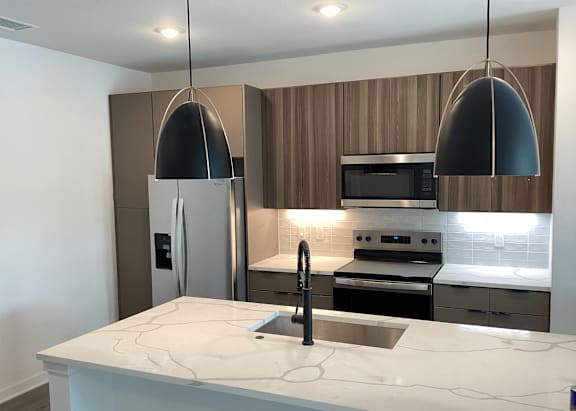 A modern kitchen with a marble countertop and stainless steel appliances at The Stadler Luxury Apartments, Florida 34210
