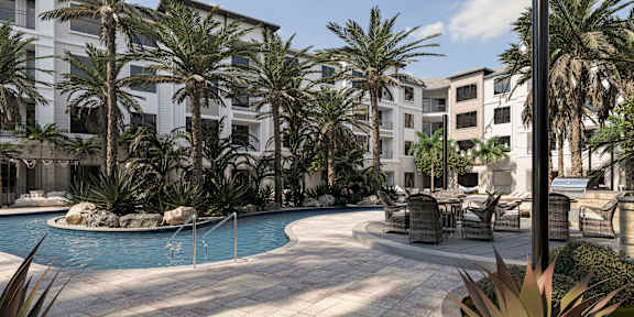A pool surrounded by palm trees and chairs at The Stadler Luxury Apartments, Bradenton, Florida