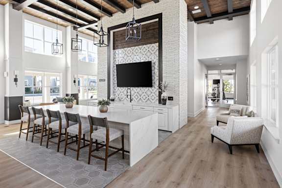 A modern kitchen with a long white island and a television mounted above it at Standard441 Luxury Apartments, Lady Lake, FL