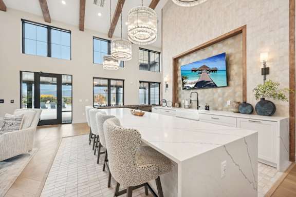 A modern kitchen with a large island and a painting of a beach scene on the wall.at The Garrison Luxury Apartment Homes, Colorado, 80817