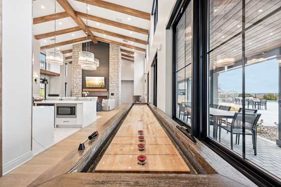 A long wooden table with bowling pins on it is in the middle of a modern kitchen and dining room.at The Garrison Luxury Apartment Homes, Fountain Colorado